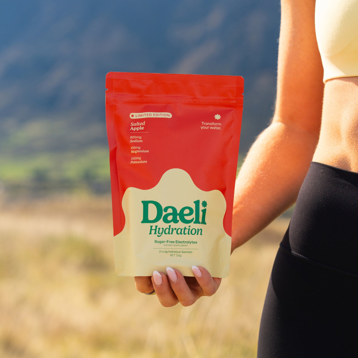 Daeli Hydration Salted Apple pouch being held by woman in activewear.