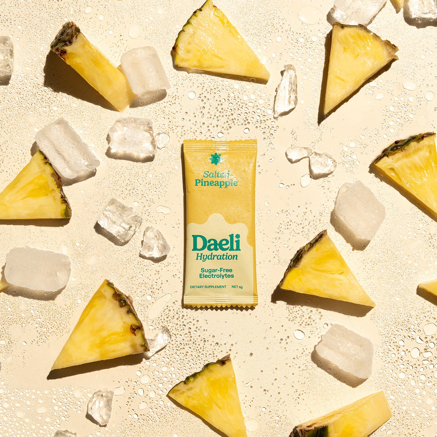 Daeli Hydration Salted Pineapple electrolyte sachet surrounded by fresh pineapple slices, ice, and salt on a light yellow surface - vibrant and hydrating flavour burst.
