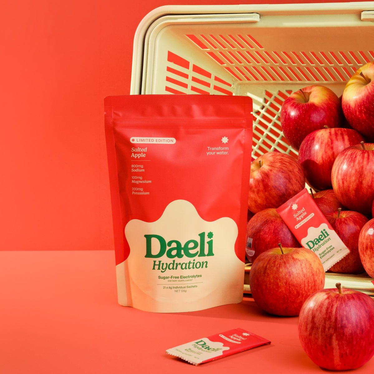 Daeli Hydration Salted Apple pouch and sachet next to a shopping basket of apples.